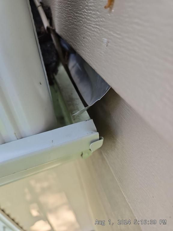 Close-up of a beige wall, white panel, and narrow gap showing a dark object inside.