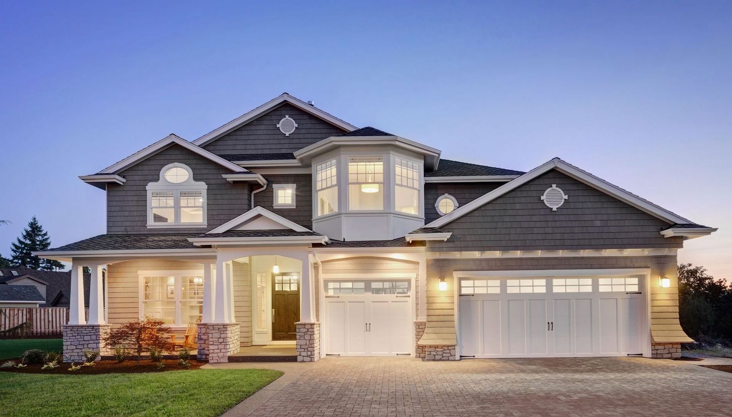 A large house with a white garage door is lit up at night.