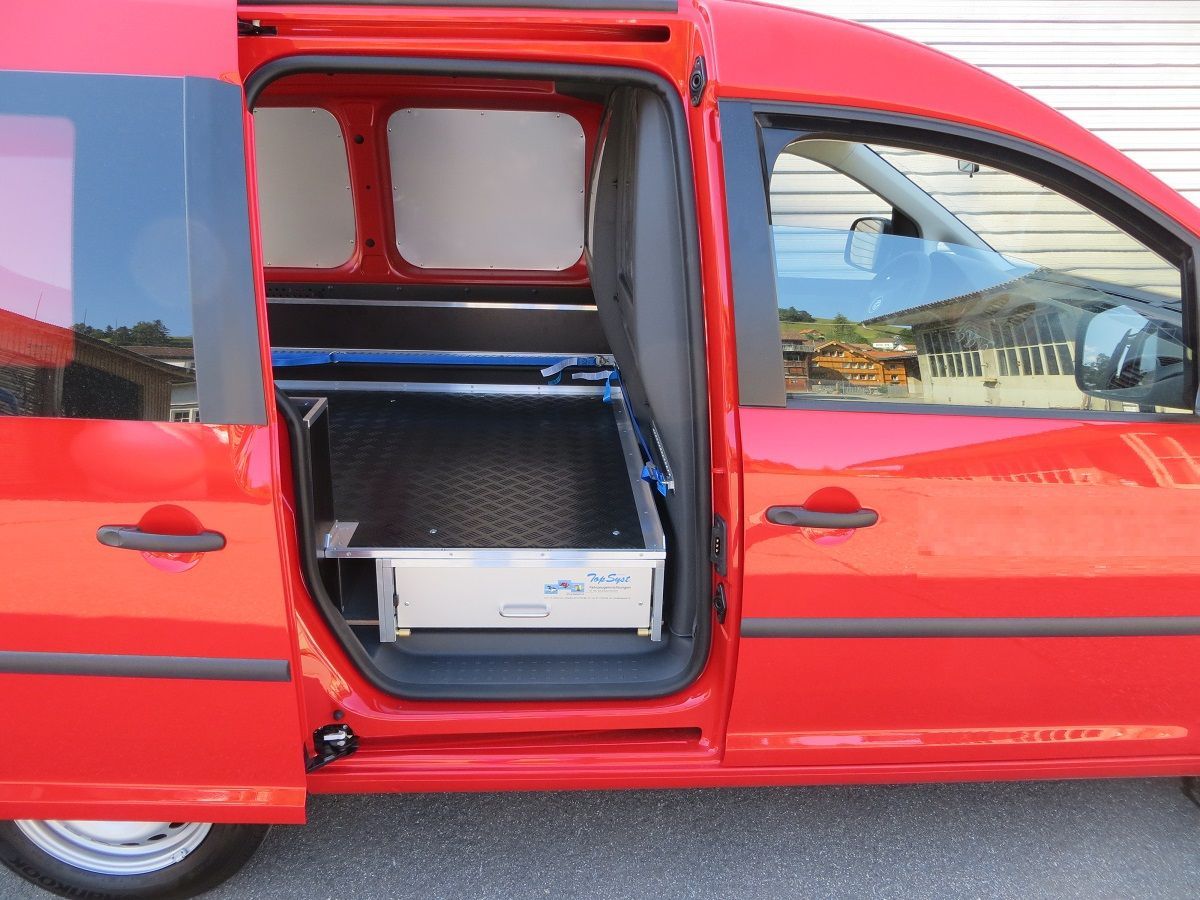 Roter Lieferwagen mit geöffneter Seitentür, die den Blick auf den Stauraum und die Ausrüstung im Inneren freigibt.