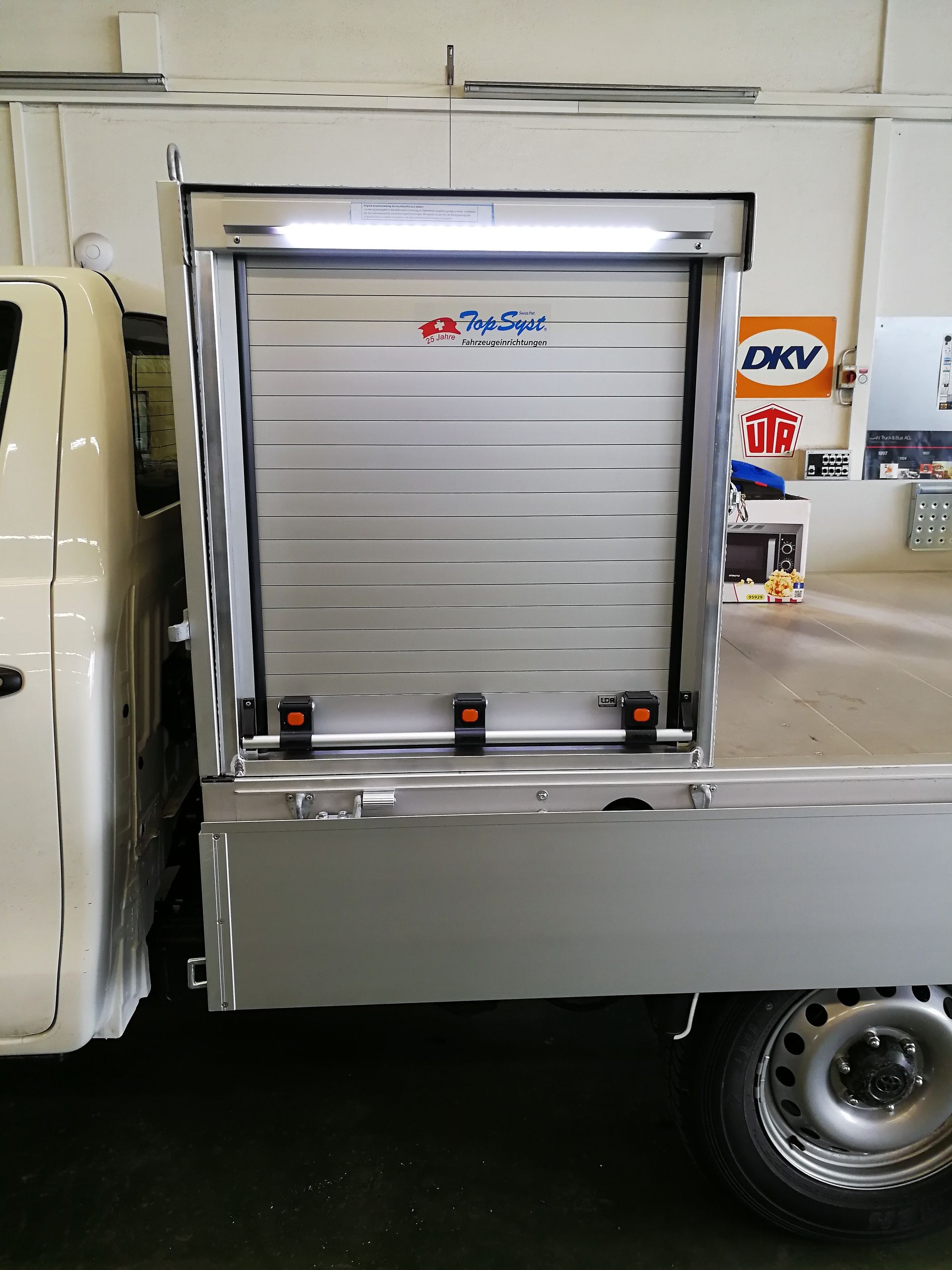Ein weißer LKW steht in einer Garage neben einem Schild mit der Aufschrift DKV