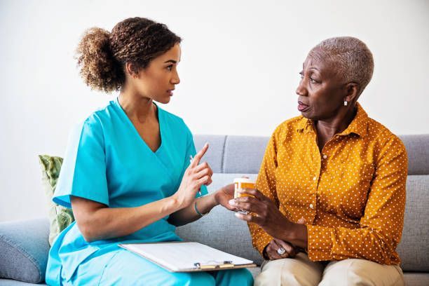 A woman is holding the hand of an elderly woman with a cane.