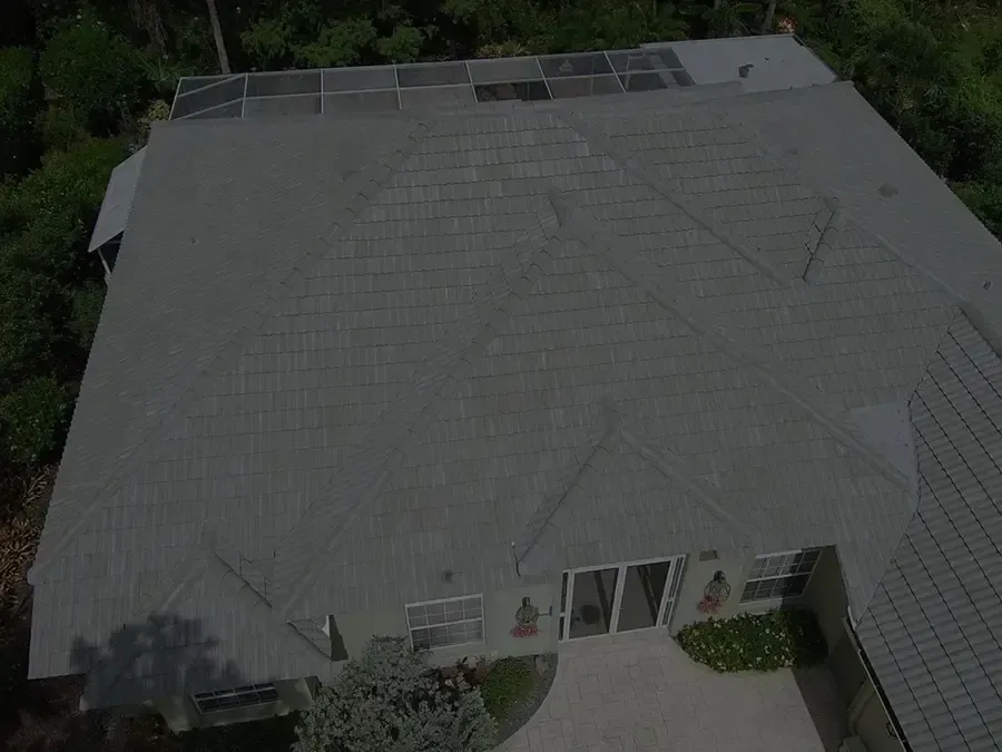 Aerial view of a gray-roofed house surrounded by trees and greenery.