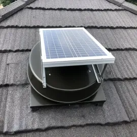 Solar panel mounted on a black roof vent on a gray shingled roof