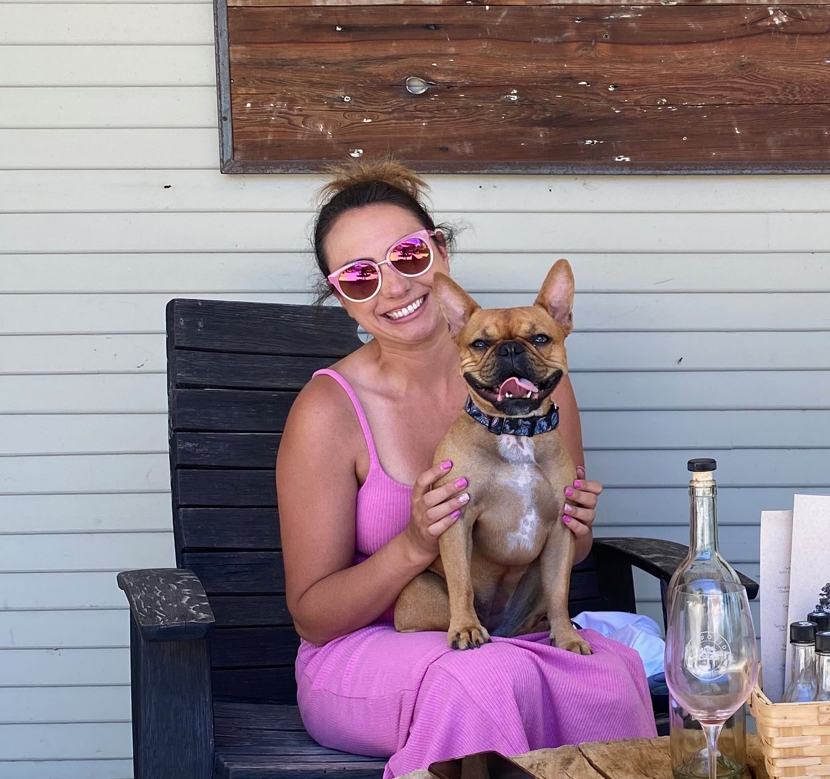 a woman in a pink dress is sitting in a chair with her dog
