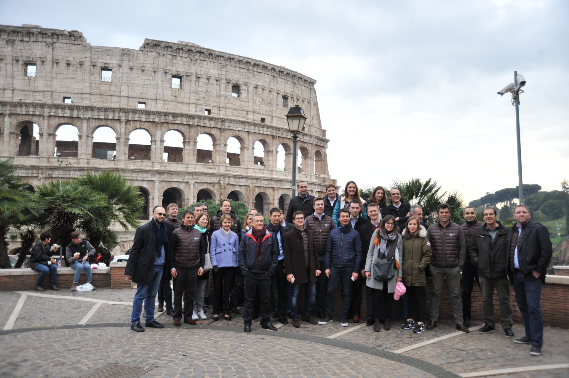 Group of people posing in front of the Colosseum in Rome on a cloudy day