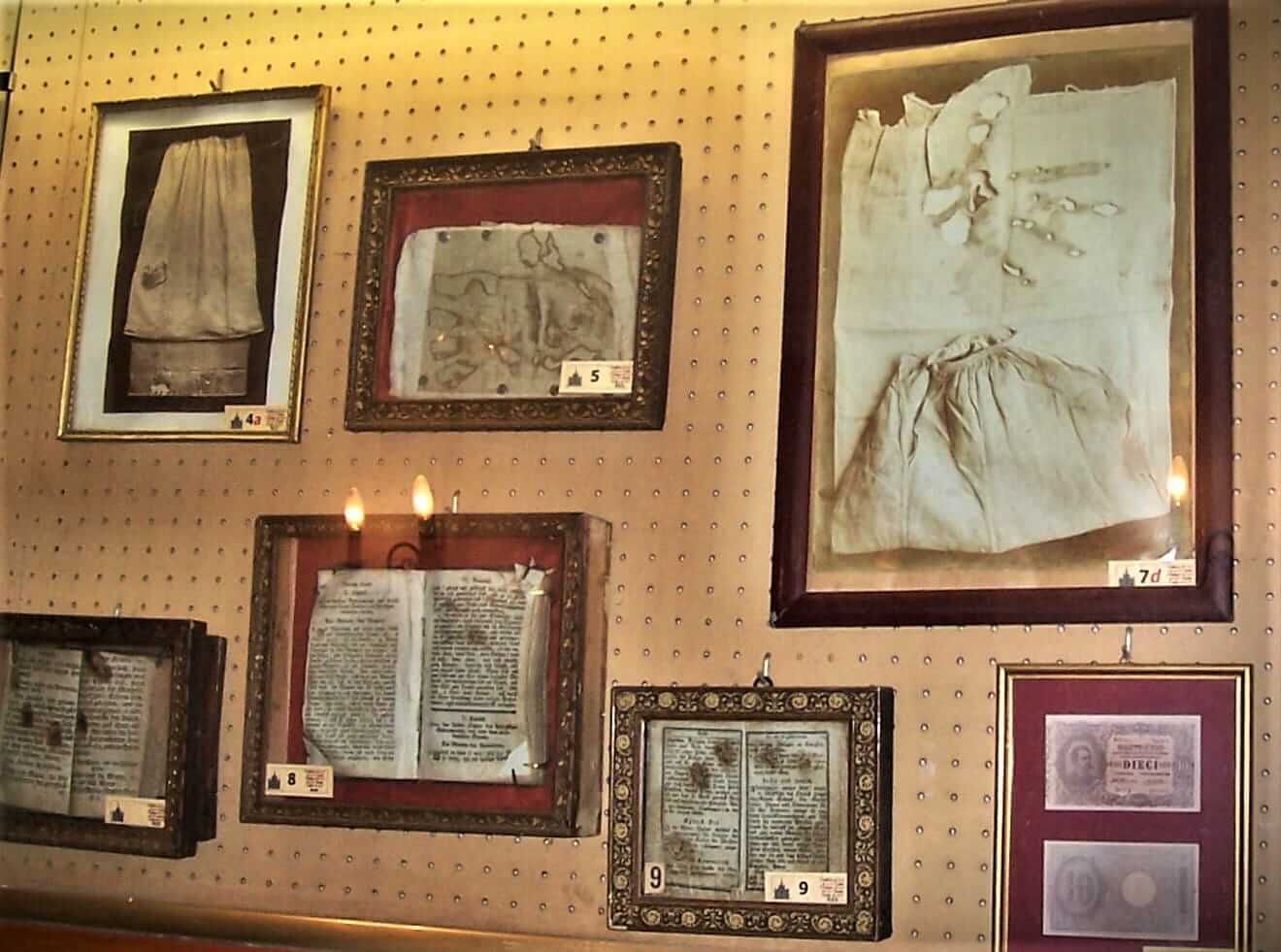 Framed antique documents and sketches displayed on a pegboard wall in a shop or museum exhibit.