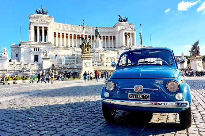 Blue vintage car in front of a grand white monument under a clear sky