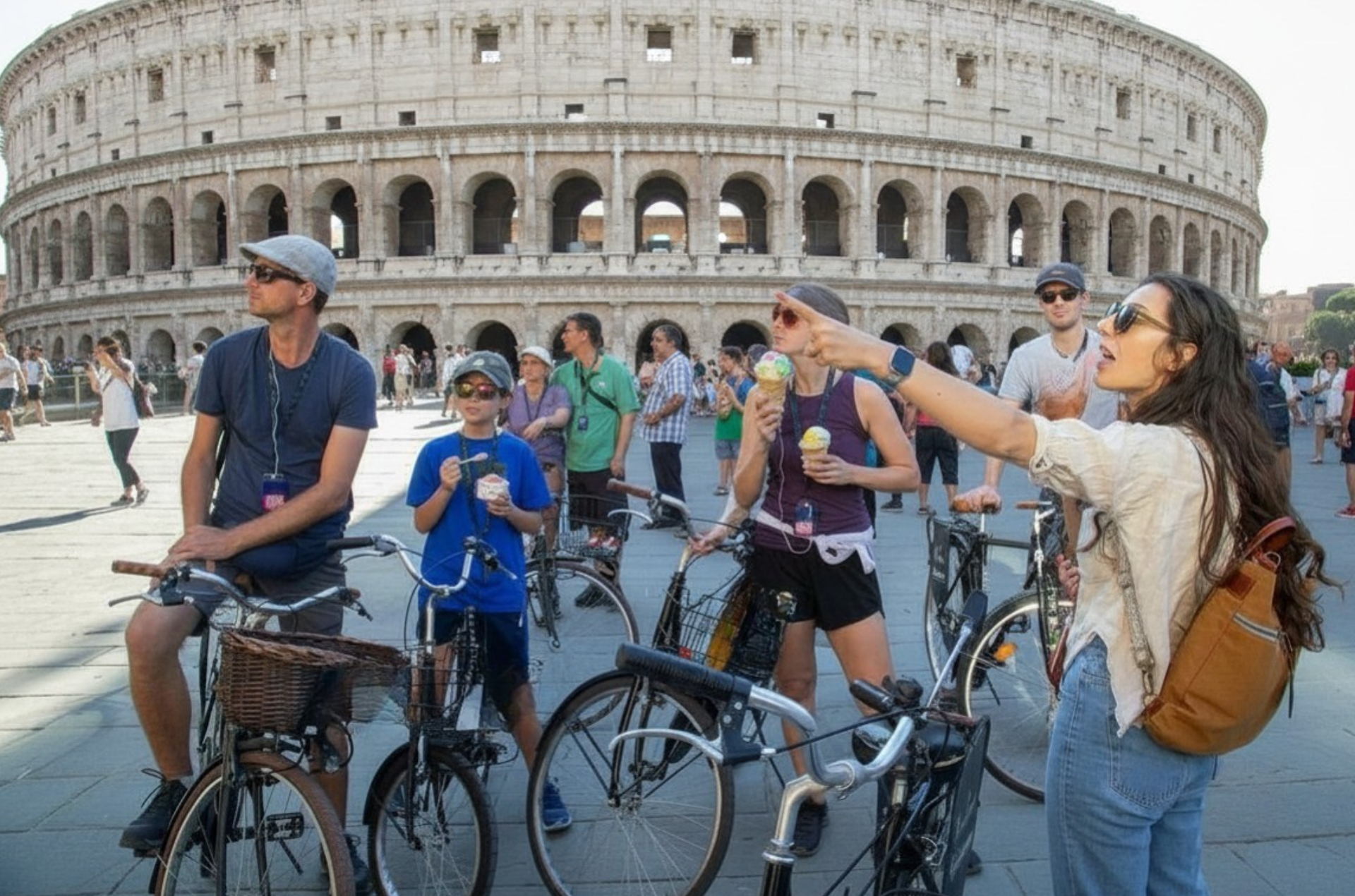 Tourists with bicycles posing in front of the Colosseum in Rome, one pointing upward
