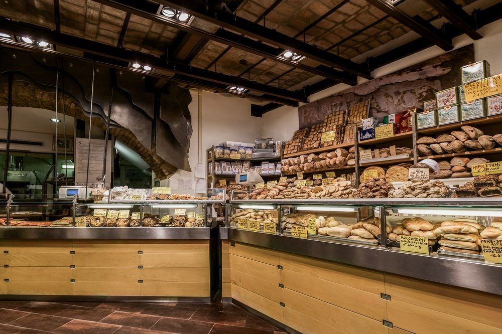 Bakery display case with assorted breads and pastries inside a warm-lit market interior