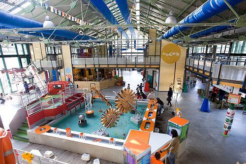 Indoor water park with colorful play structures, slides, and a splash pool under a high ceiling.