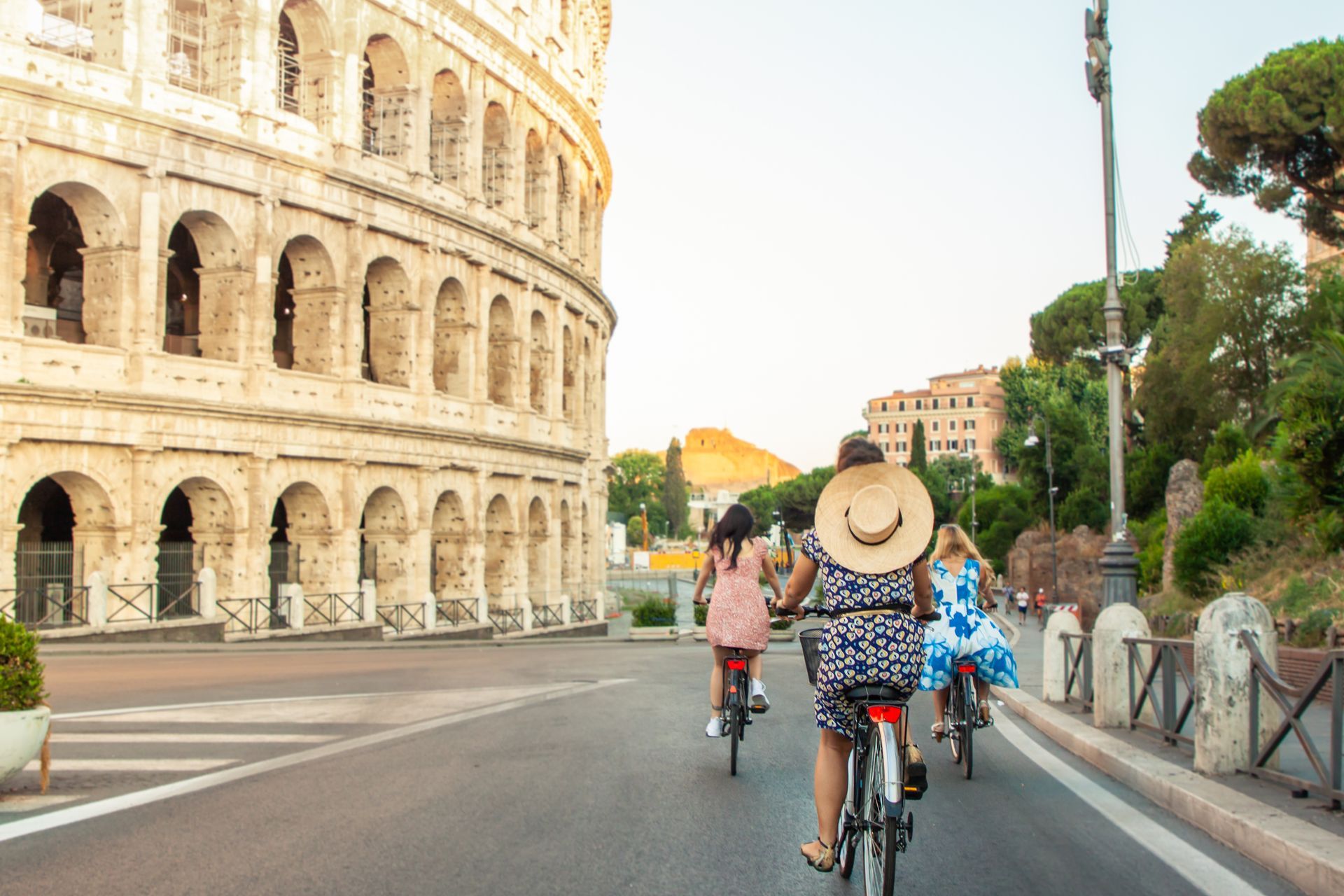 Cyclists riding past the Colosseum on a sunny street in Rome
