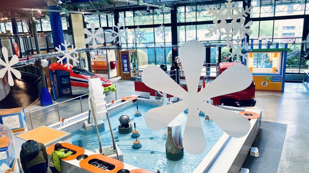 Interior of a modern industrial exhibit with a large white propeller model and colorful machinery displays