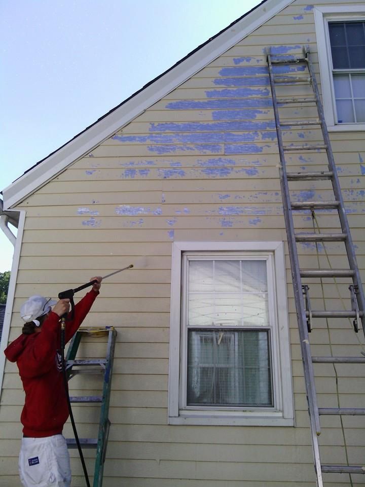 A person spraying paint on the side of a house