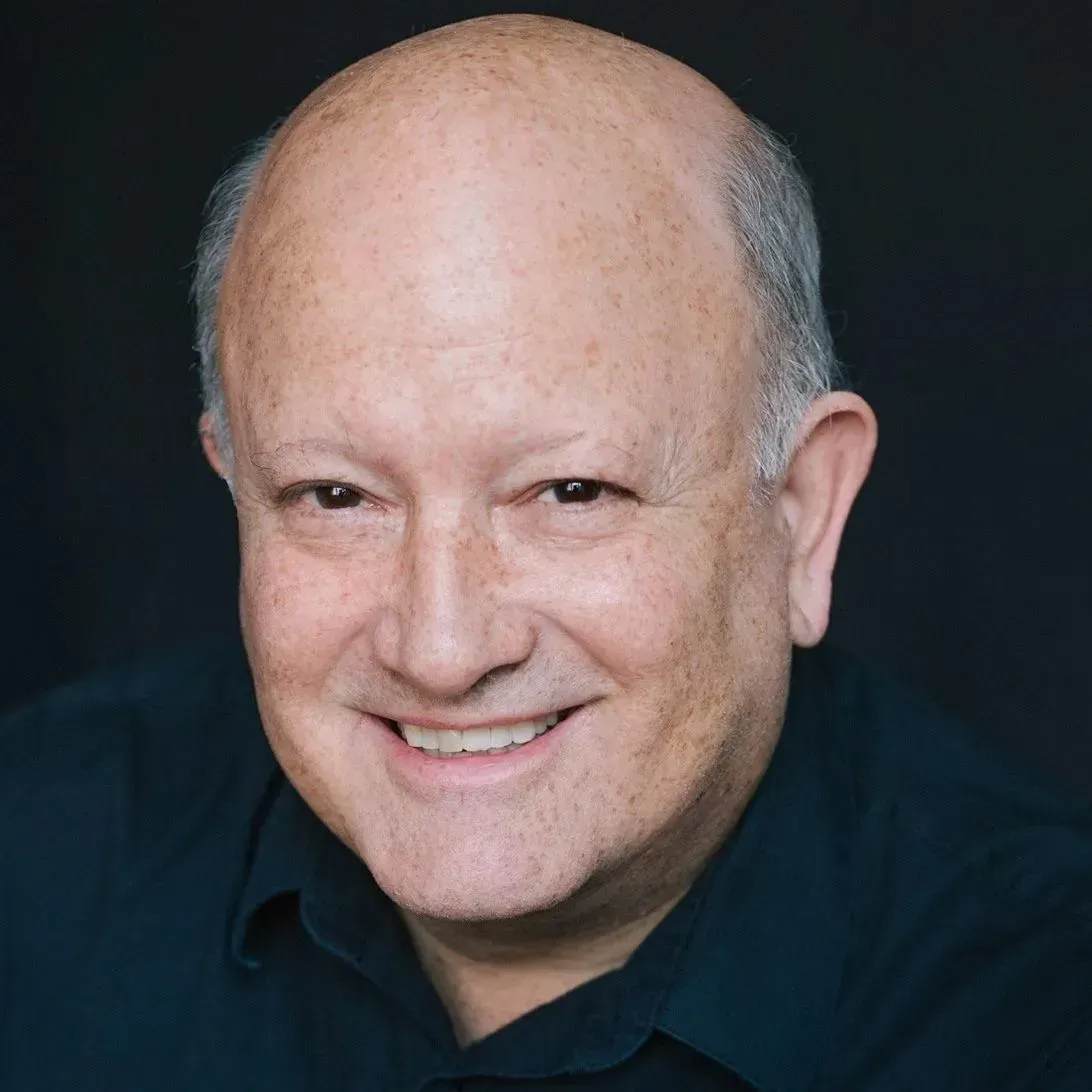 Smiling bald man in a dark shirt against a dark background
