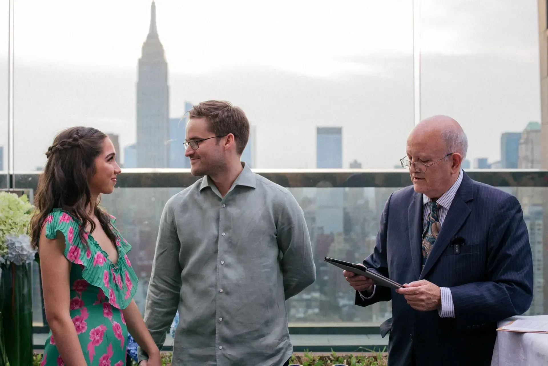 Three people on a rooftop terrace, with the Empire State Building in the background.