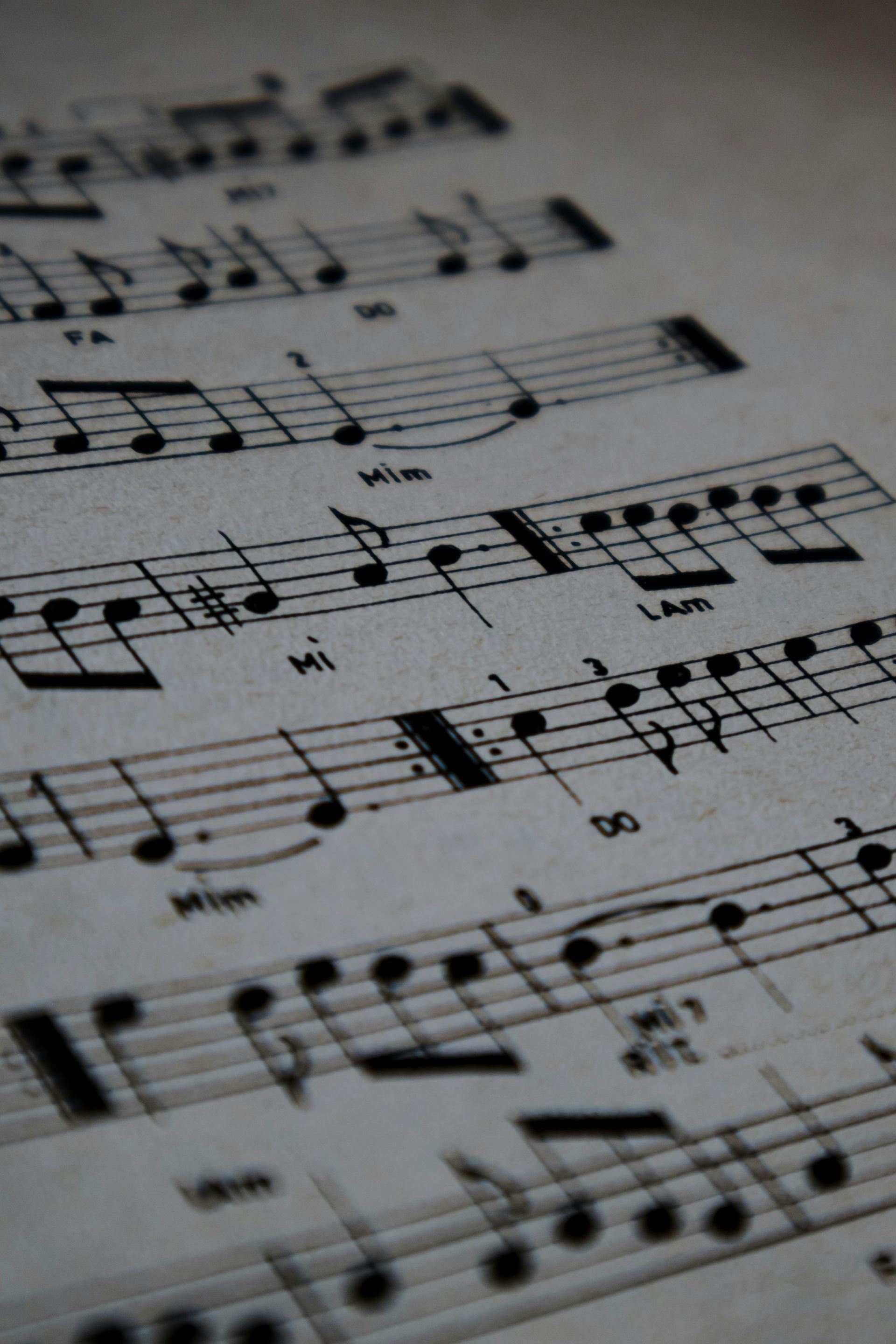 Close-up of sheet music with black notes on white paper, slightly angled and softly lit