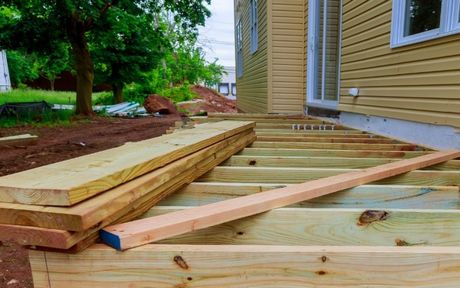 deck building carpenters installing new deck outside residential home with all wood 4x4.