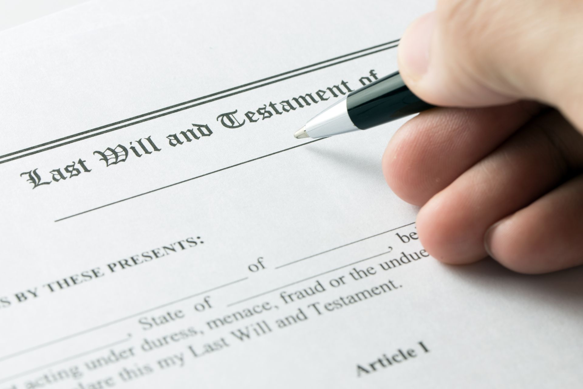 A person is signing a last will and testament with a pen