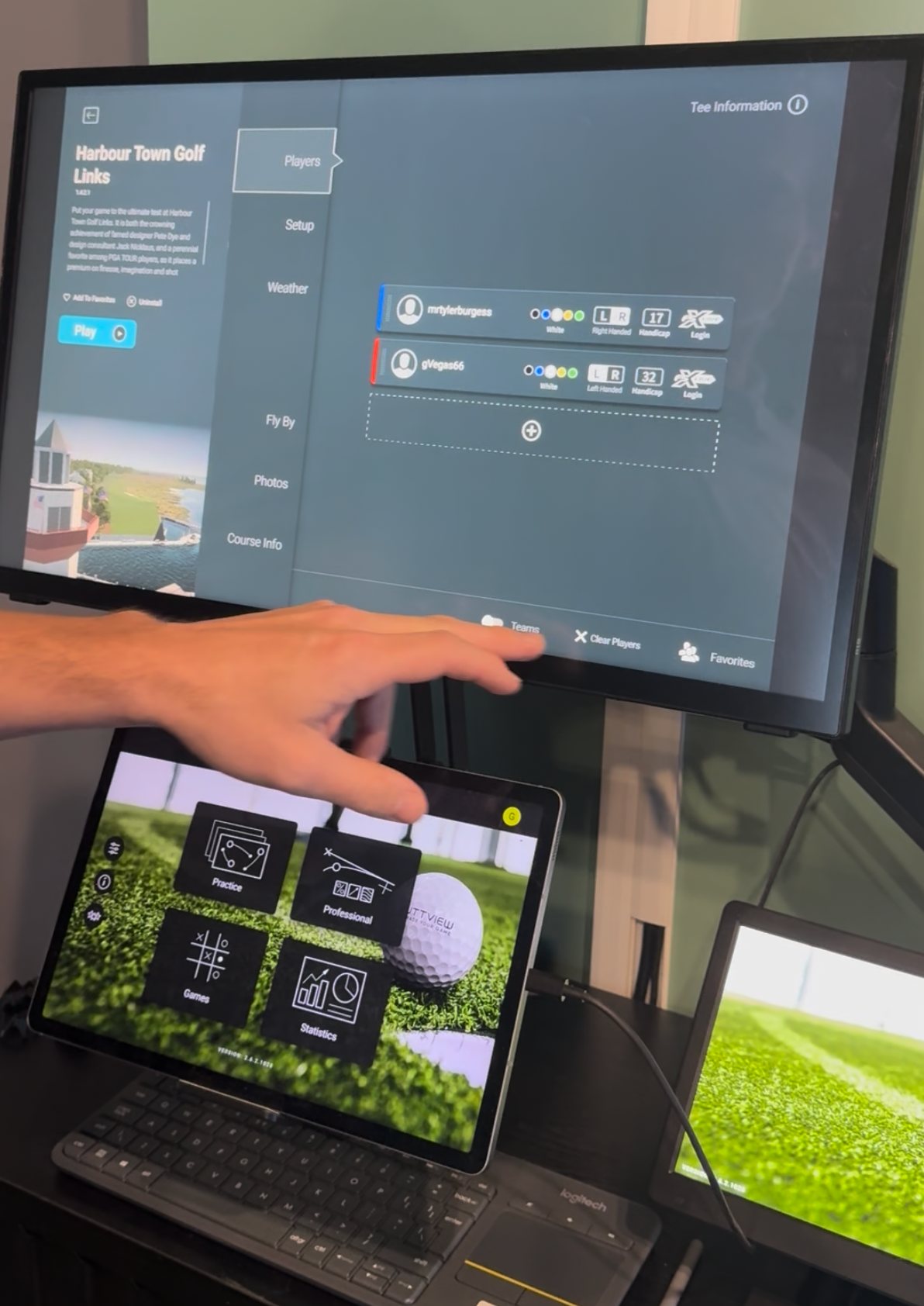 Hand adjusting a monitor showing display settings beside two laptops on a desk