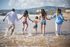 Family holding hands and running into ocean waves on a sunny beach