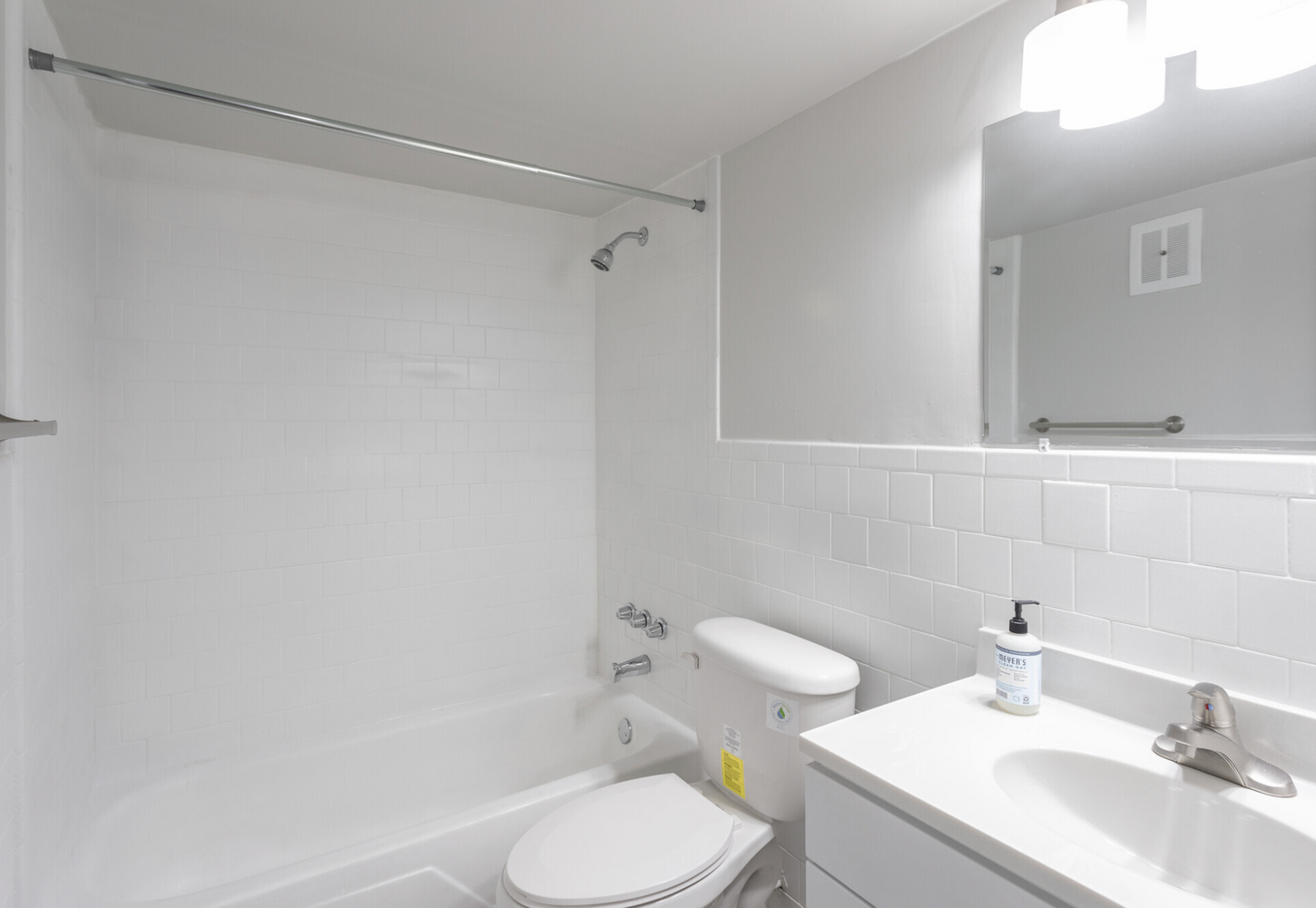 A bathroom with a toilet , sink , shower and mirror.
