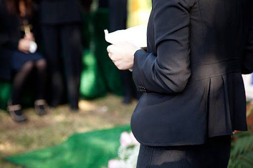 Person reading eulogy to a crowd