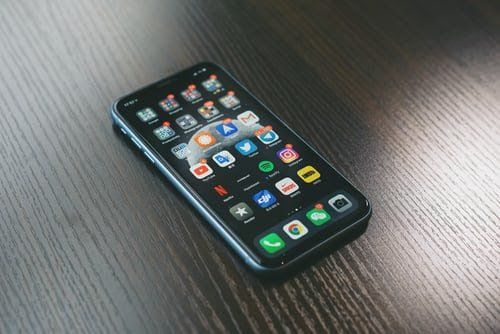 Phone with many apps on wooden table