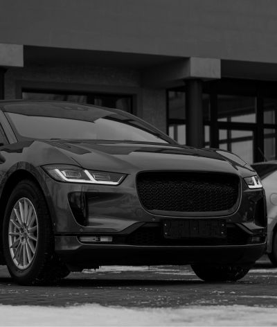 A black and white photo of a jaguar i pace parked in front of a building.
