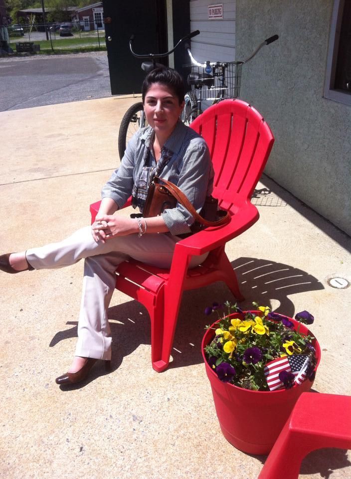 A woman sits in a red chair next to a pot of flowers | InTown Auto Care