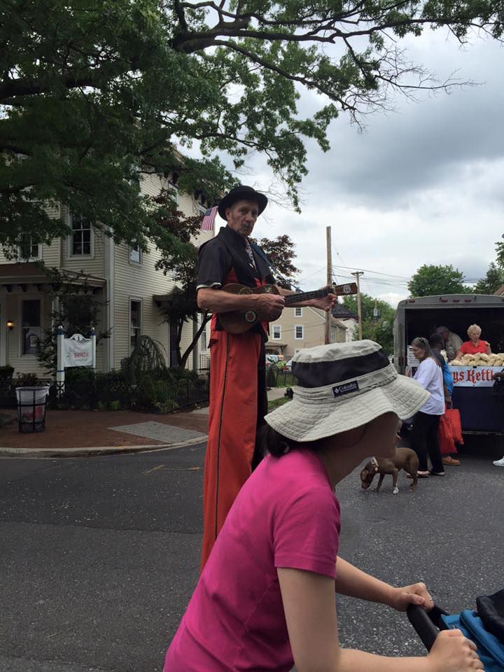A man on stilts is playing a guitar while a woman looks on | InTown Auto Care