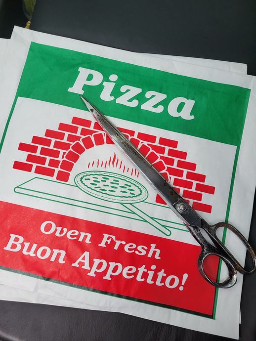 A pair of scissors sitting on top of a pizza box