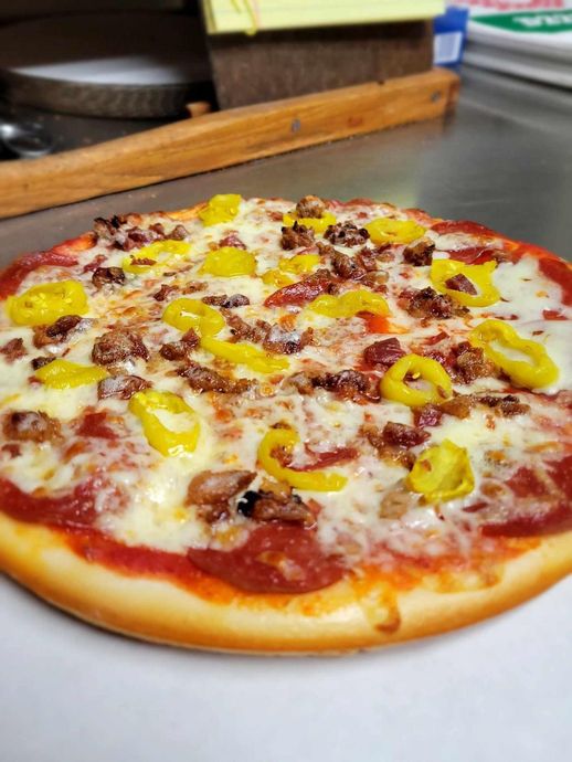 A pizza with pepperoni , sausage , and cheese is sitting on a table.