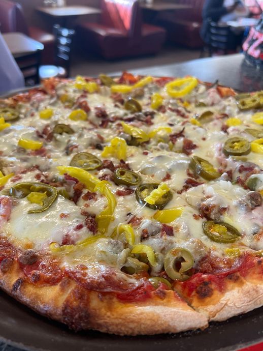 A pizza with pepperoni , jalapenos , and cheese on a pan.