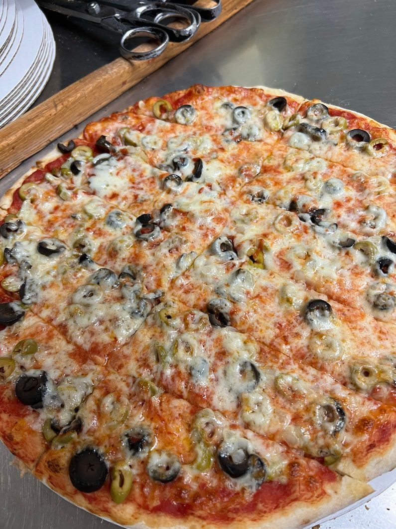 A pizza with olives and cheese is sitting on a table.