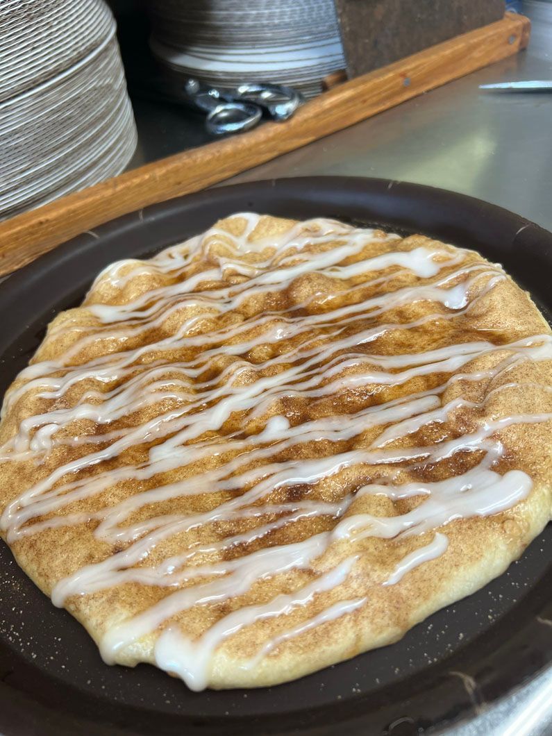 A cinnamon bread with icing on it is on a plate.