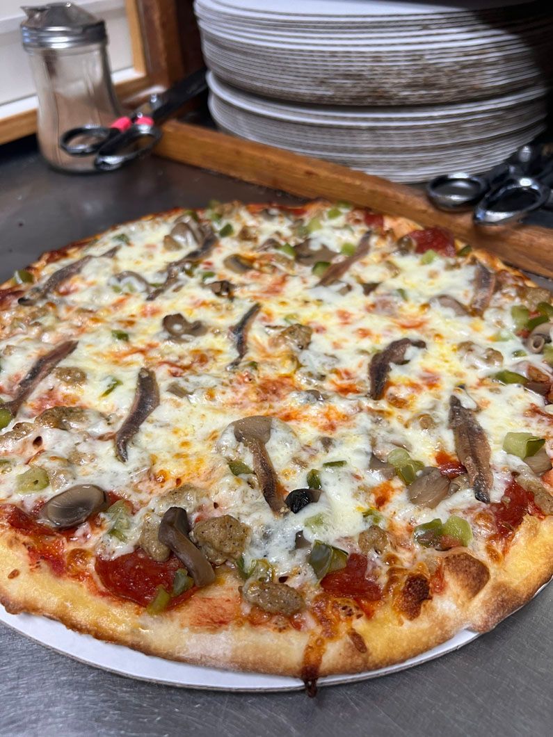 A pizza with a lot of toppings on it is on a plate on a table.