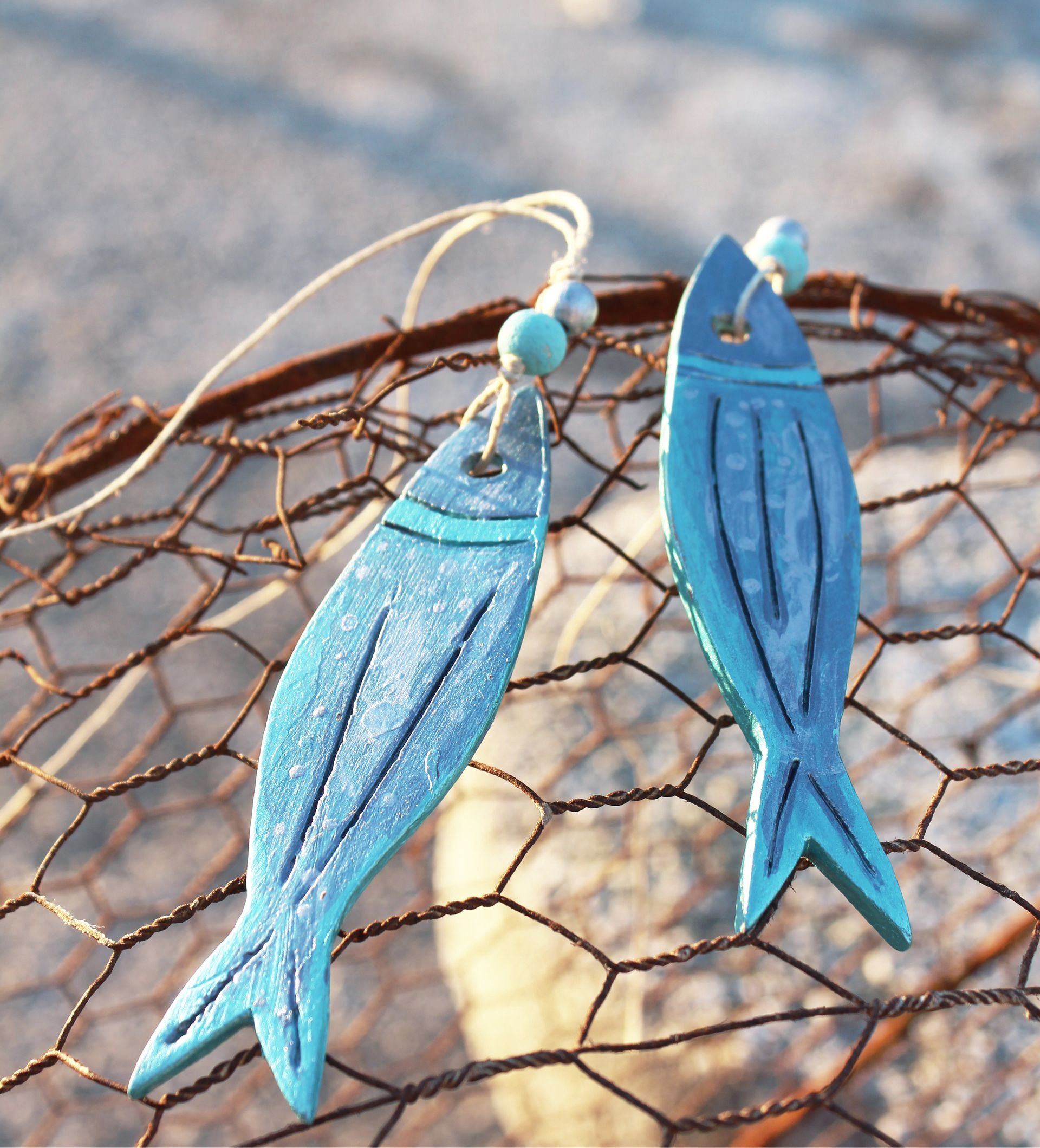 A pair of blue fish earrings are sitting on a fishing net