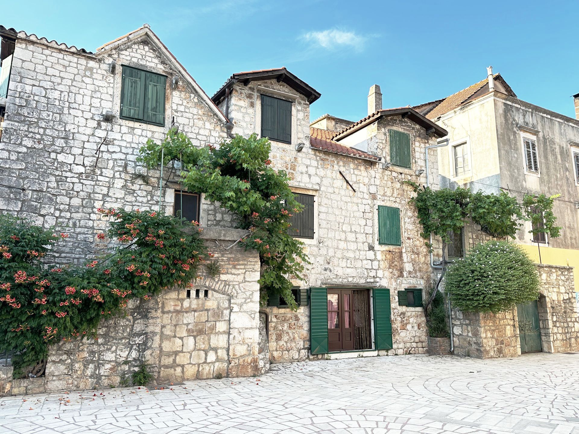 A row of stone buildings with green shutters on the windows.