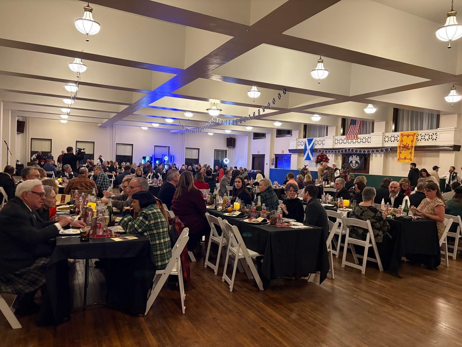 Large room with people seated at tables, likely a formal dinner.