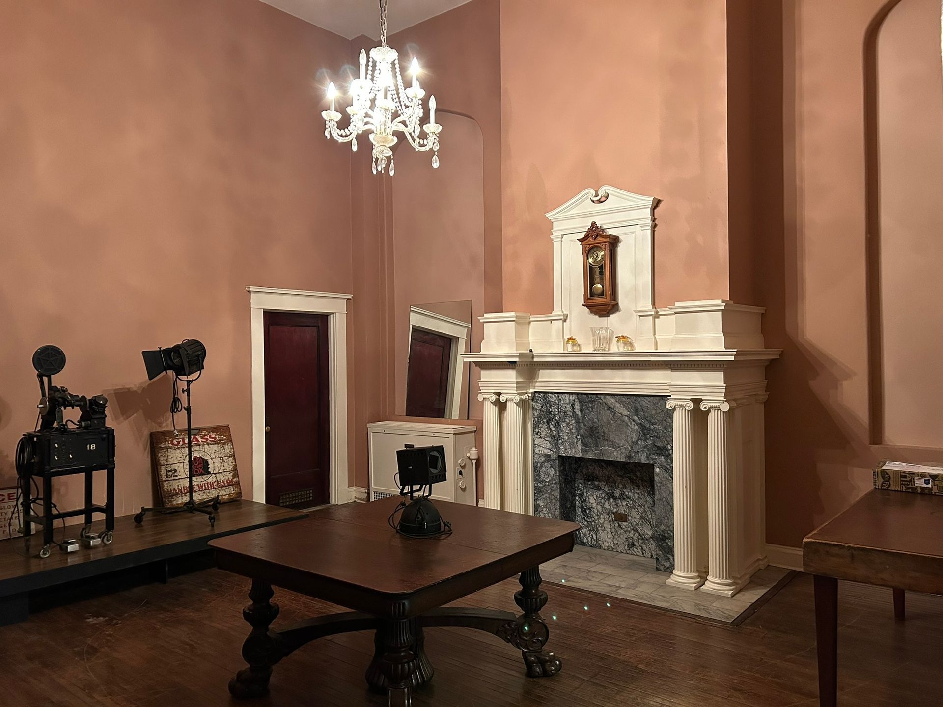 A living room with a fireplace , table , chairs and a chandelier.