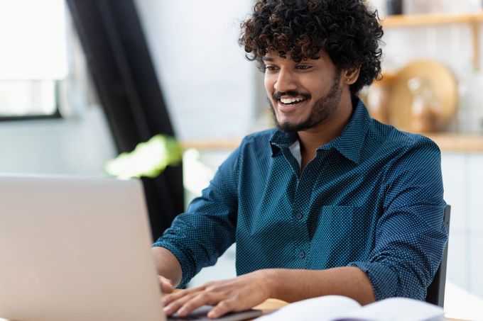 Smiling person typing on a laptop in a bright home office