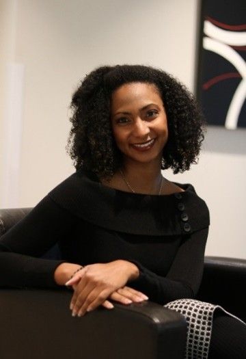 Smiling woman seated on a black couch in a modern indoor setting