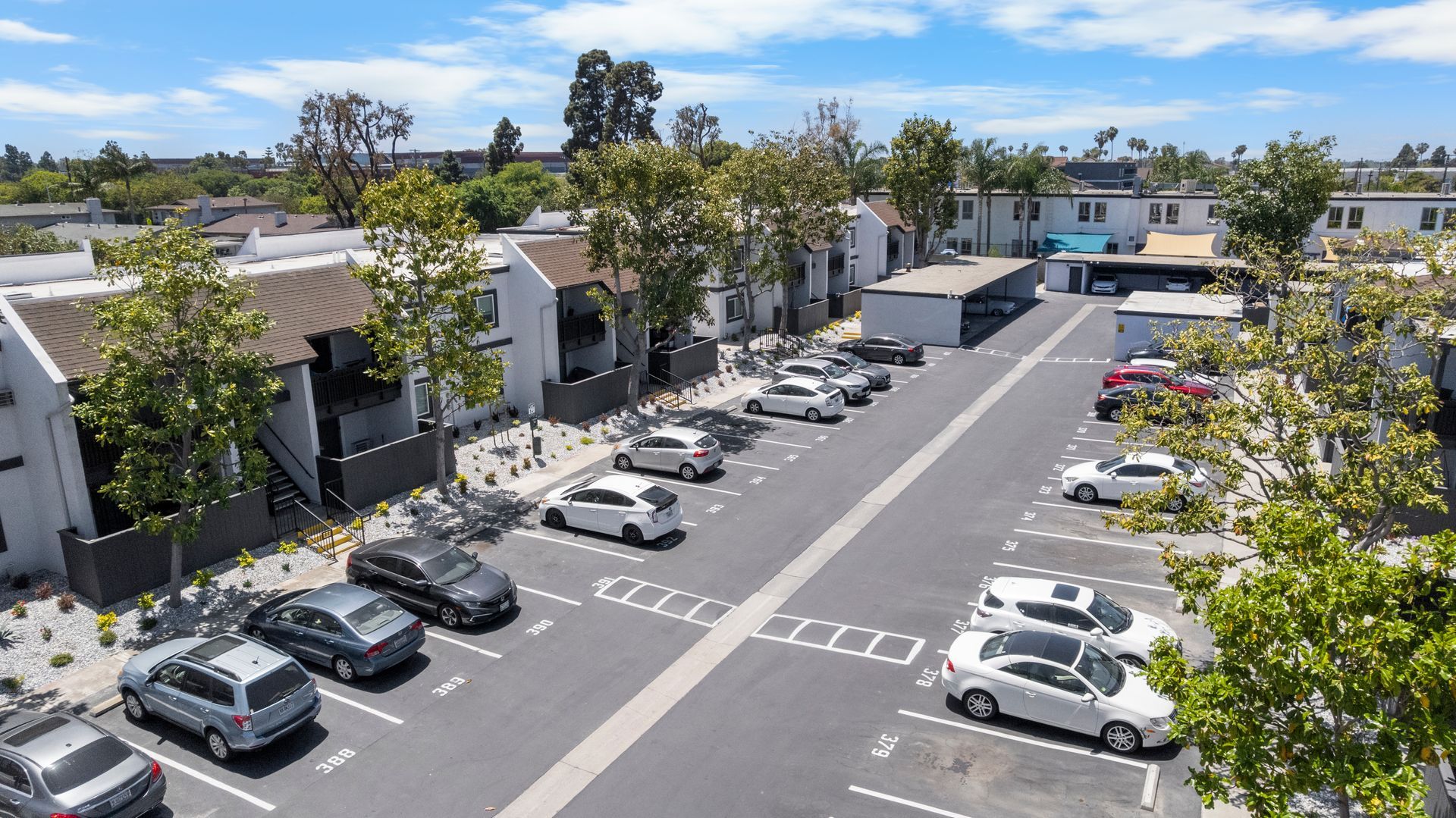 An aerial view of a parking lot with cars parked in front of a building.