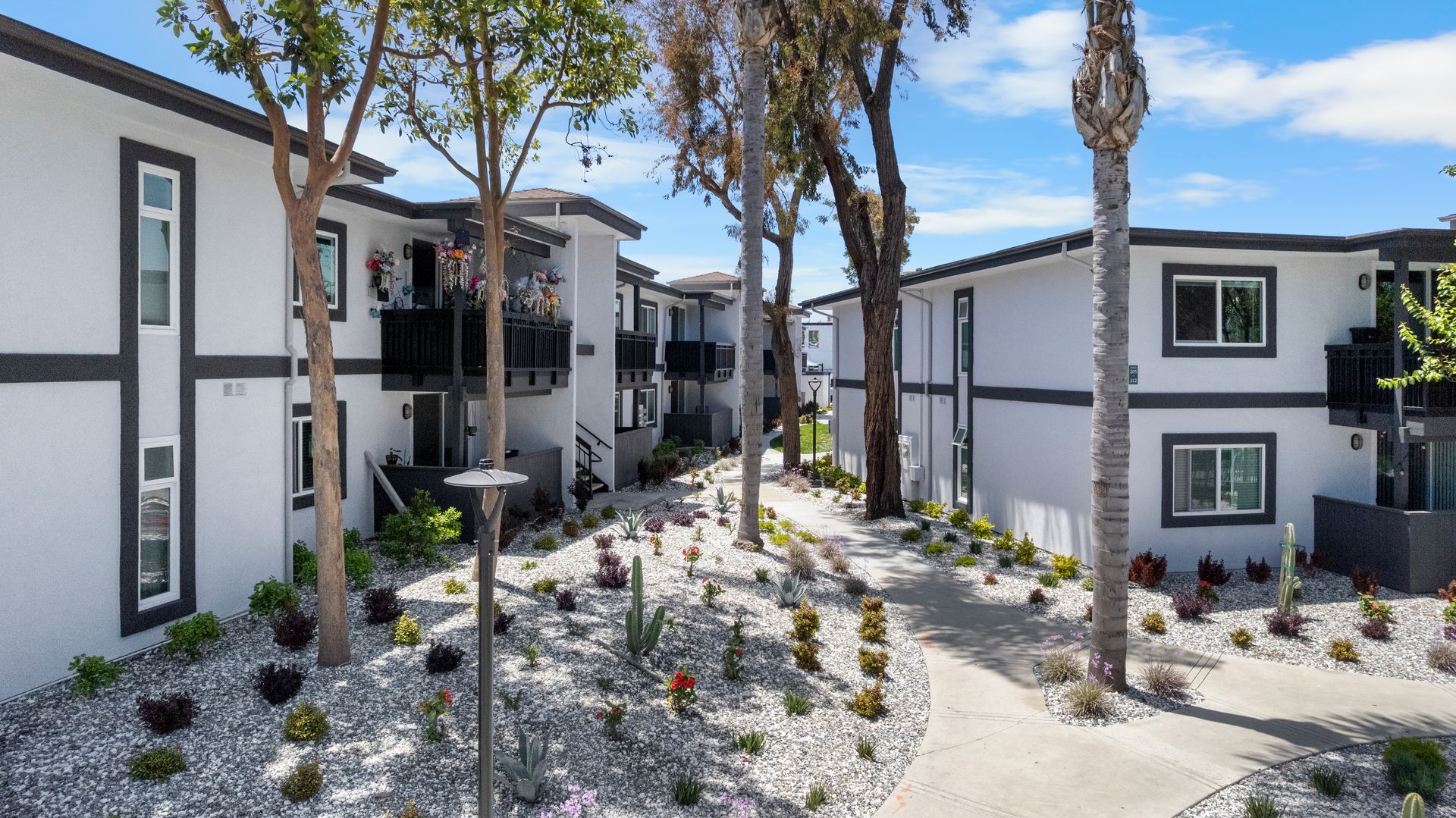 A row of white apartment buildings with trees in front of them.