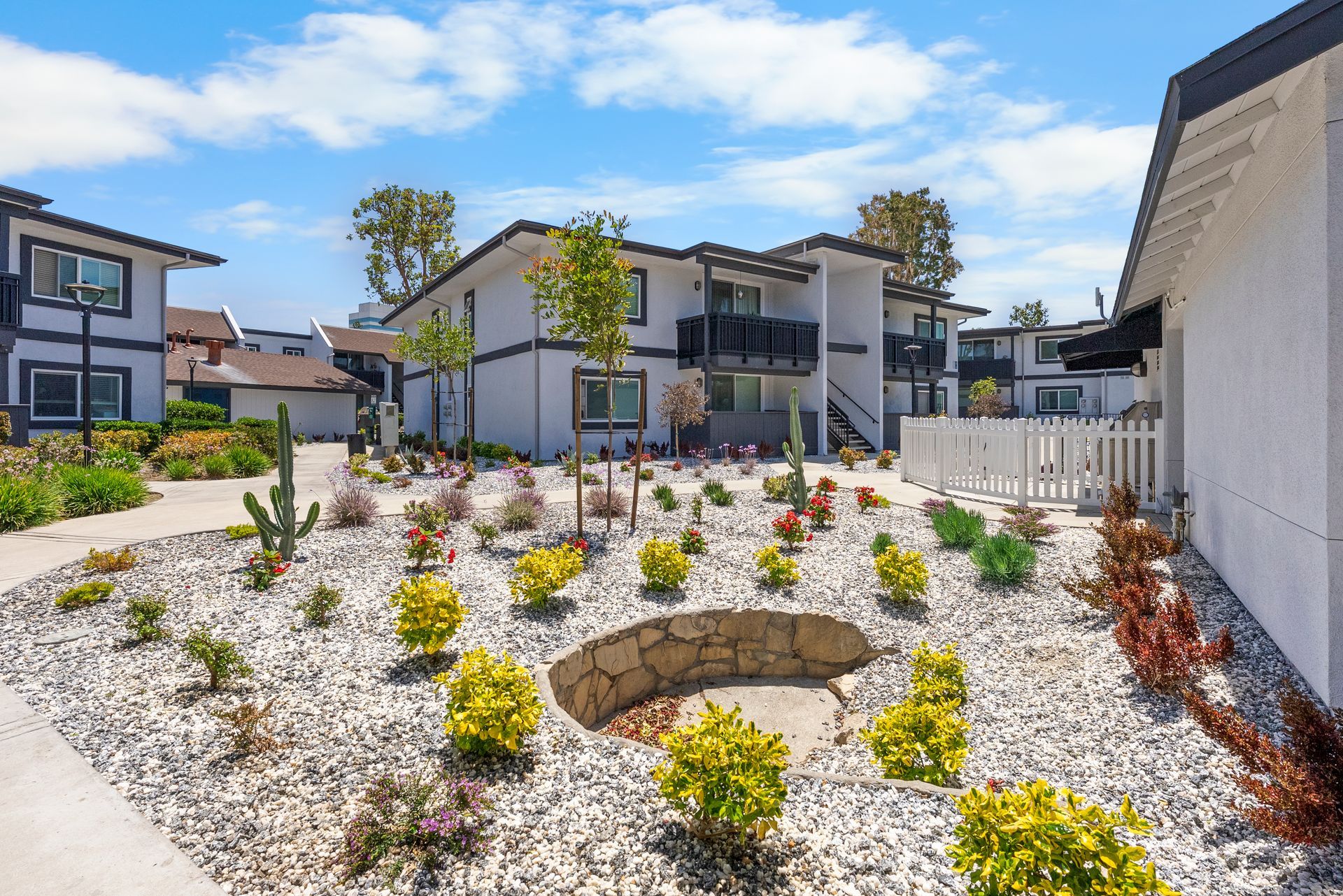 There is a fire pit in the middle of a garden in front of a building.