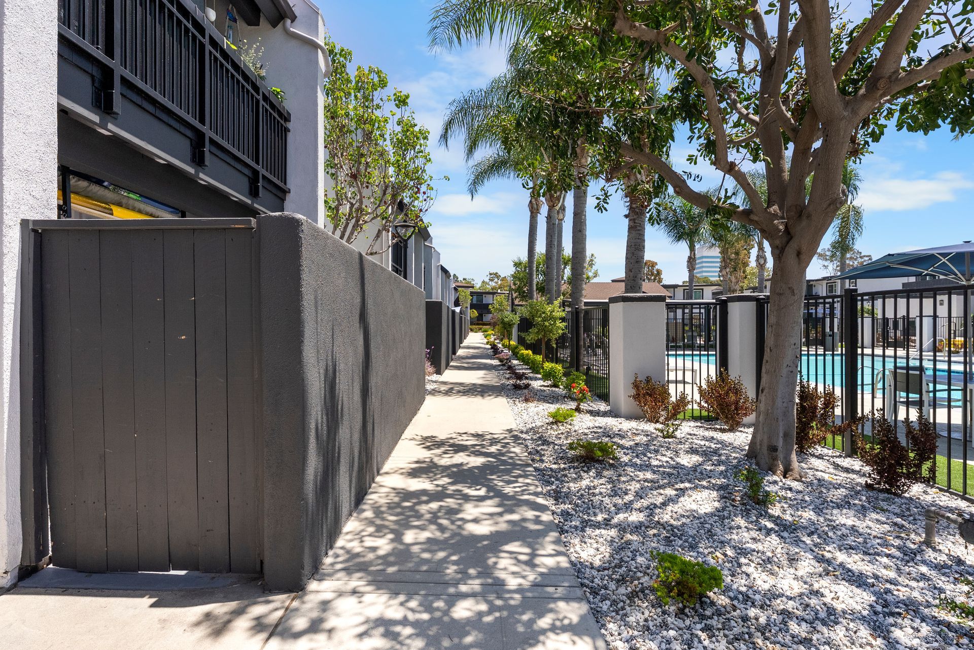 A fence surrounds a walkway leading to a swimming pool.