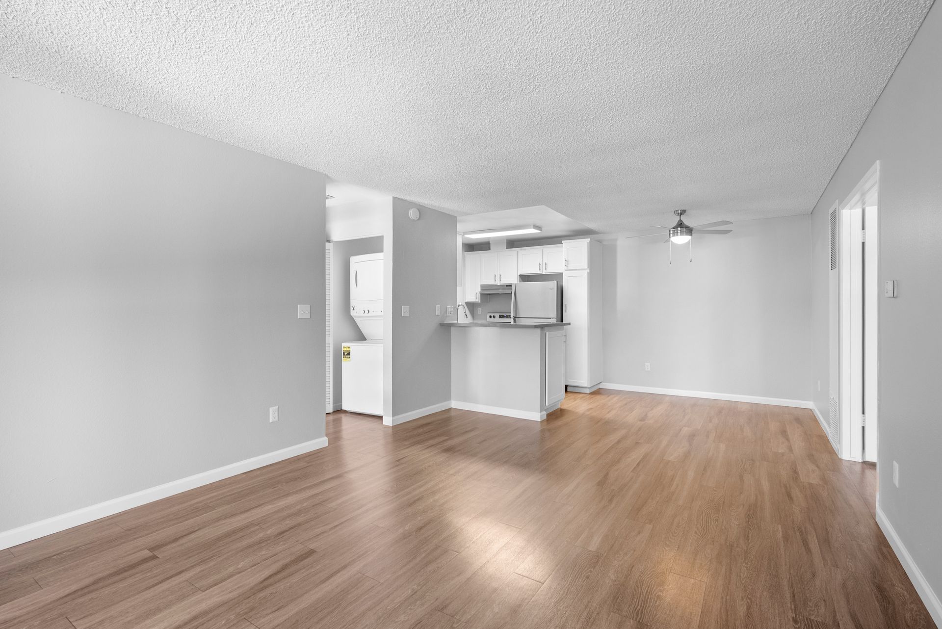 An empty living room with hardwood floors and white walls.