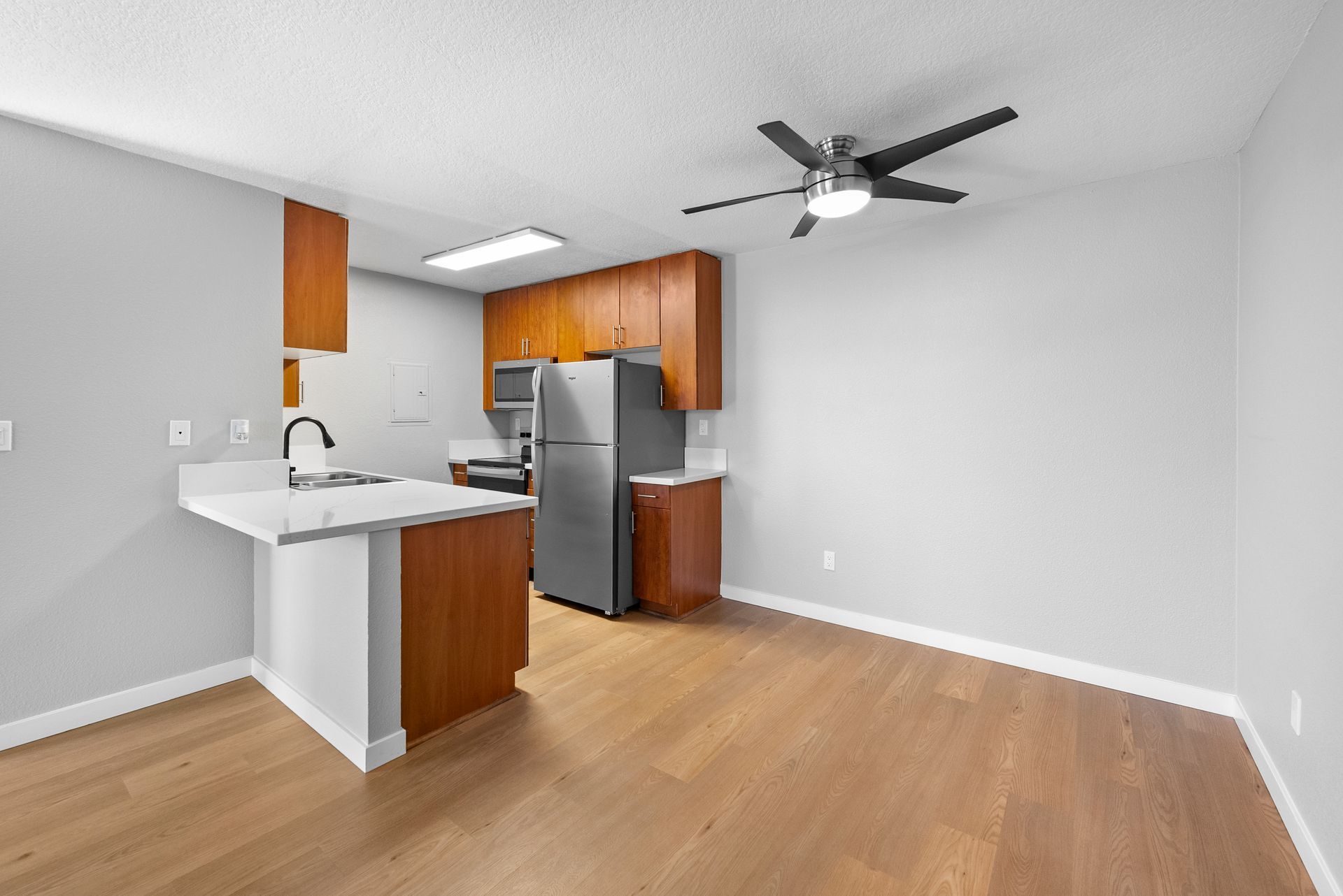 A kitchen with a refrigerator , sink , and ceiling fan.