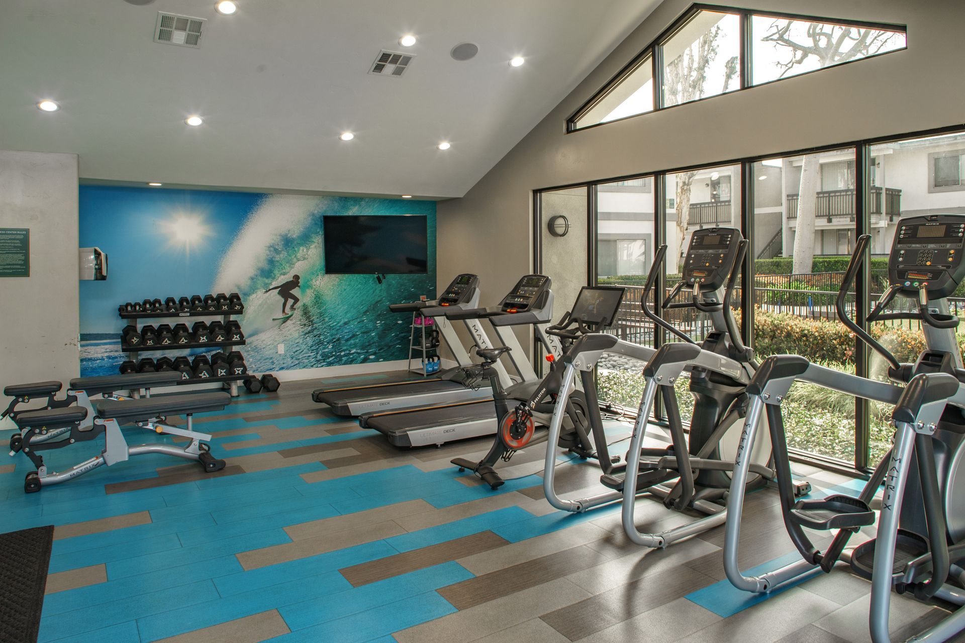 A gym with a lot of exercise equipment and a large window.