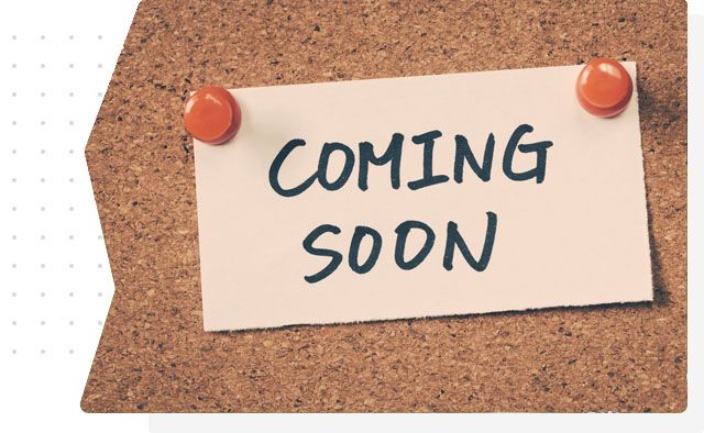 A piece of paper that says coming soon is pinned to a cork board A piece of paper that says coming soon is pinned to a cork board